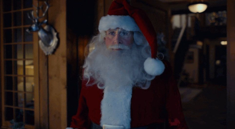 a man dressed as santa claus standing in front of a door