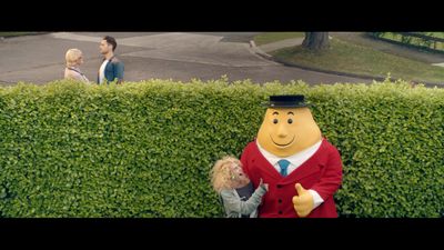 a man in a suit and tie standing next to a hedge