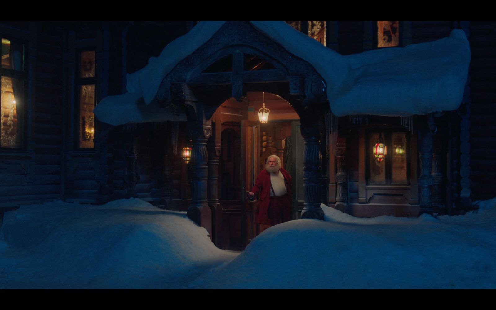 a woman standing outside of a house in the snow