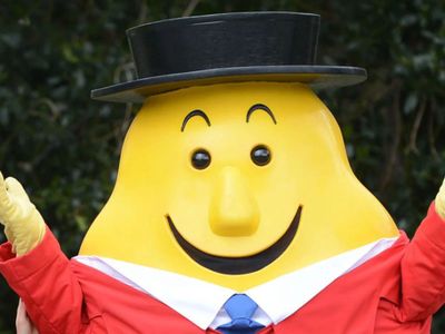 a man in a top hat and tie standing next to a large yellow character