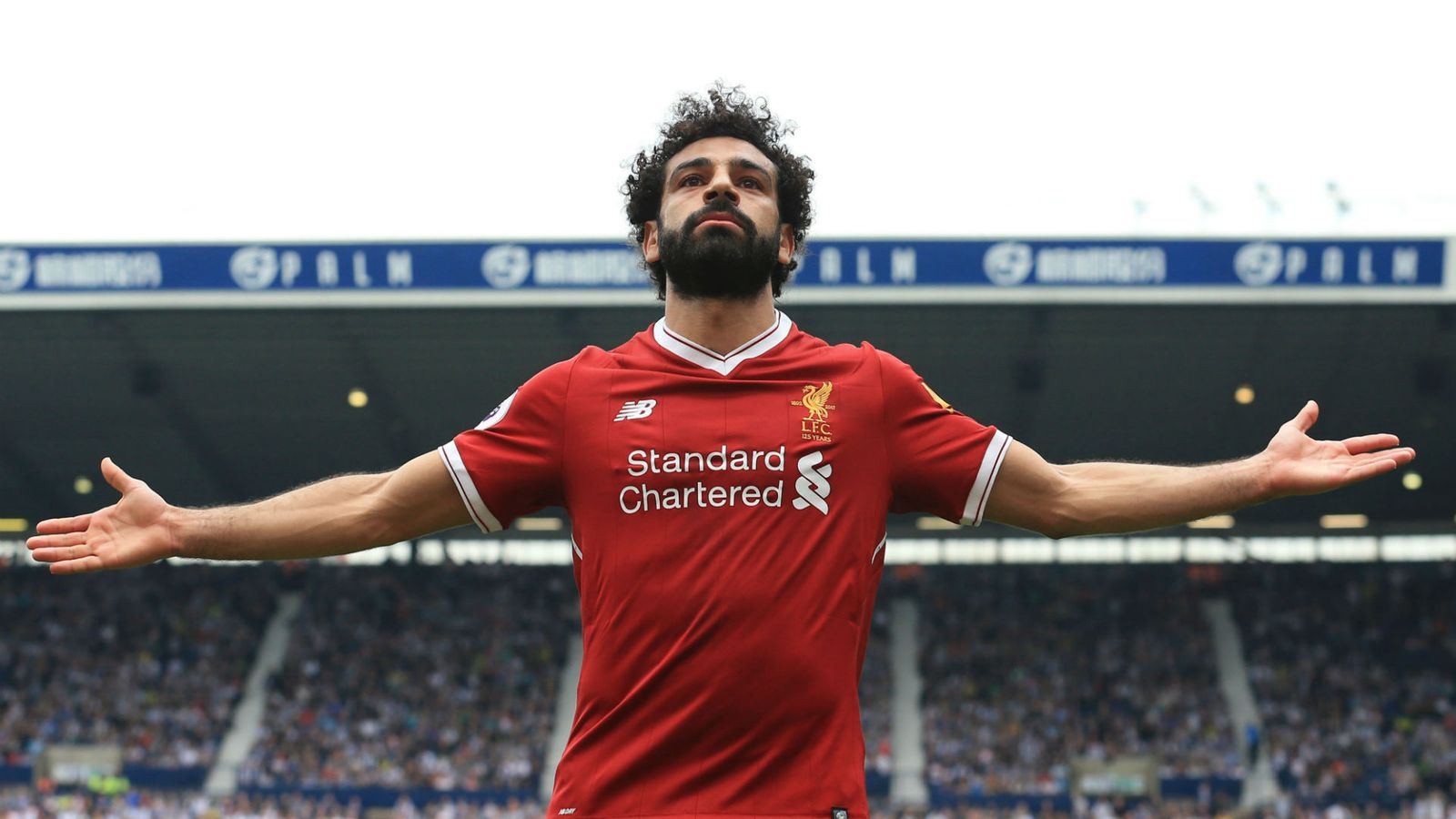 a man with his arms outstretched in front of a stadium