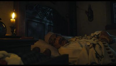 a man laying in a bed next to a candle