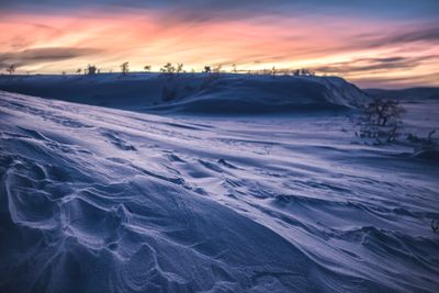 a snow covered hill with a sunset in the background