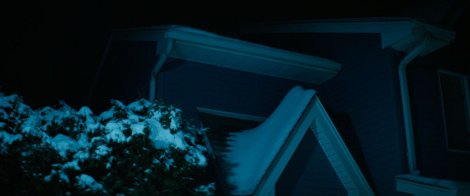 a snow covered roof of a house at night