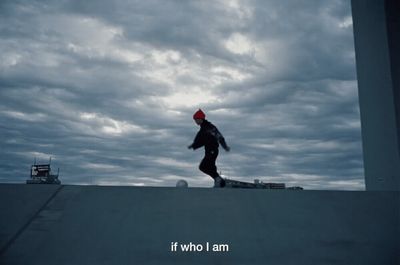 a person in a red hat is skateboarding on a cloudy day