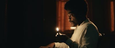 a man holding a lit candle in a dark room