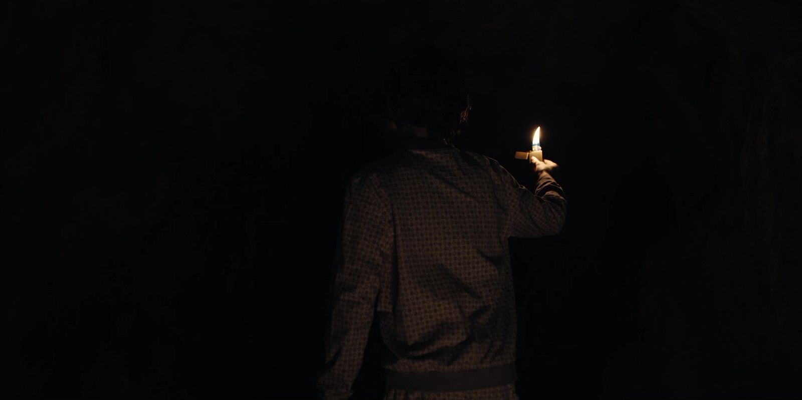 a man holding a lit candle in the dark