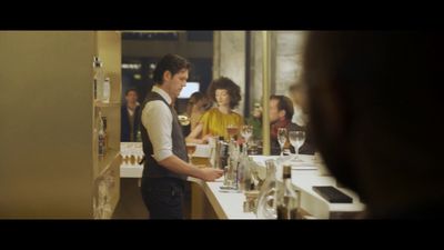 a man standing in front of a counter filled with wine glasses