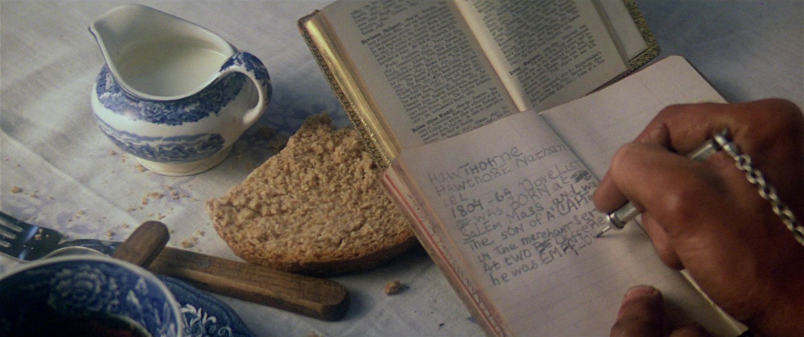 a person writing on a book next to a cup of coffee