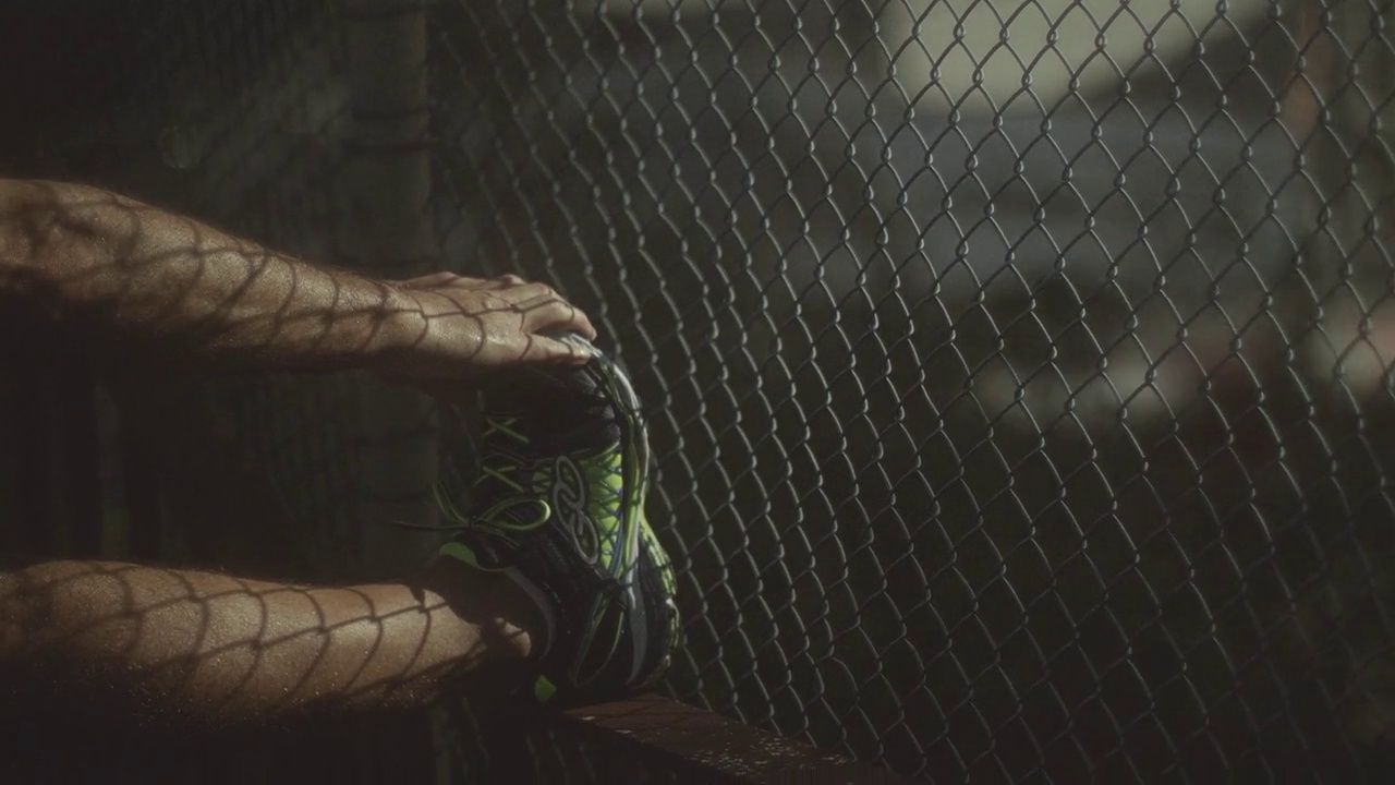 a person holding a tennis shoe in front of a fence