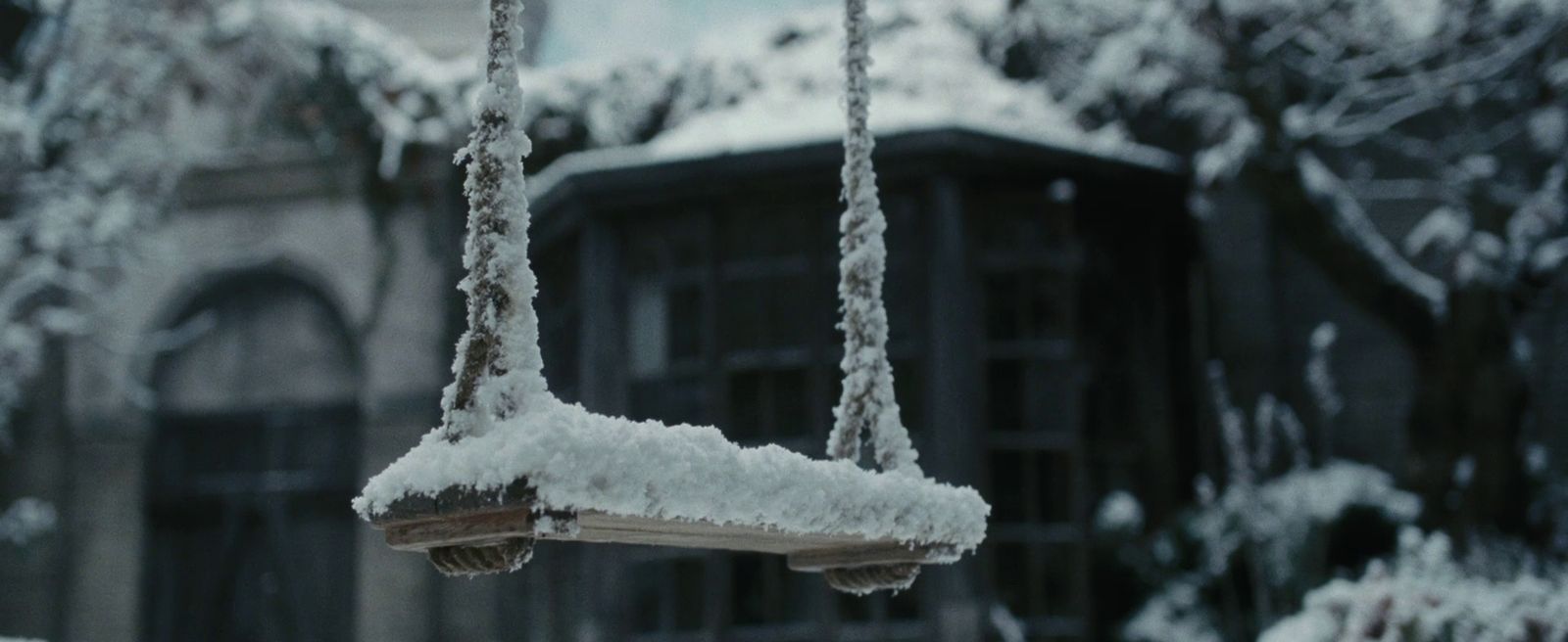 a swing covered in snow in front of a house