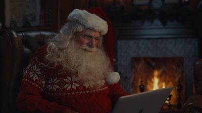 a man dressed as santa claus using a laptop computer