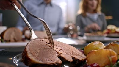 a person cutting a piece of meat on a plate