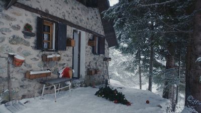 a house in the snow with a christmas tree in front of it