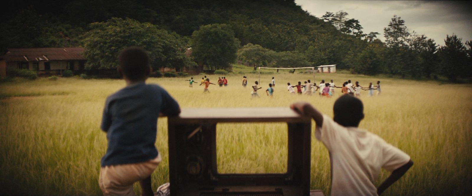 a group of people standing in a field next to a tv