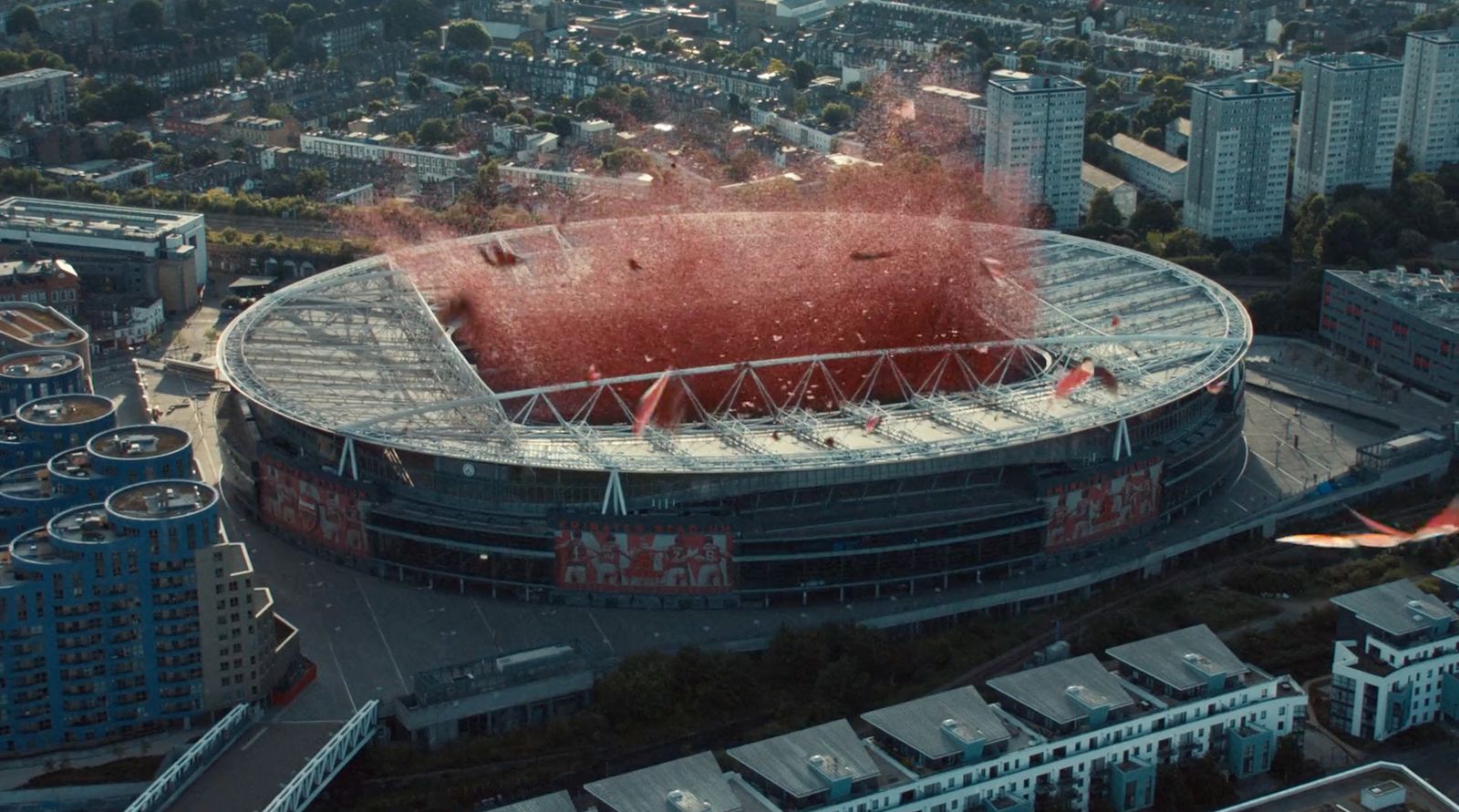 an aerial view of a soccer stadium with a red smoke trail coming out of the