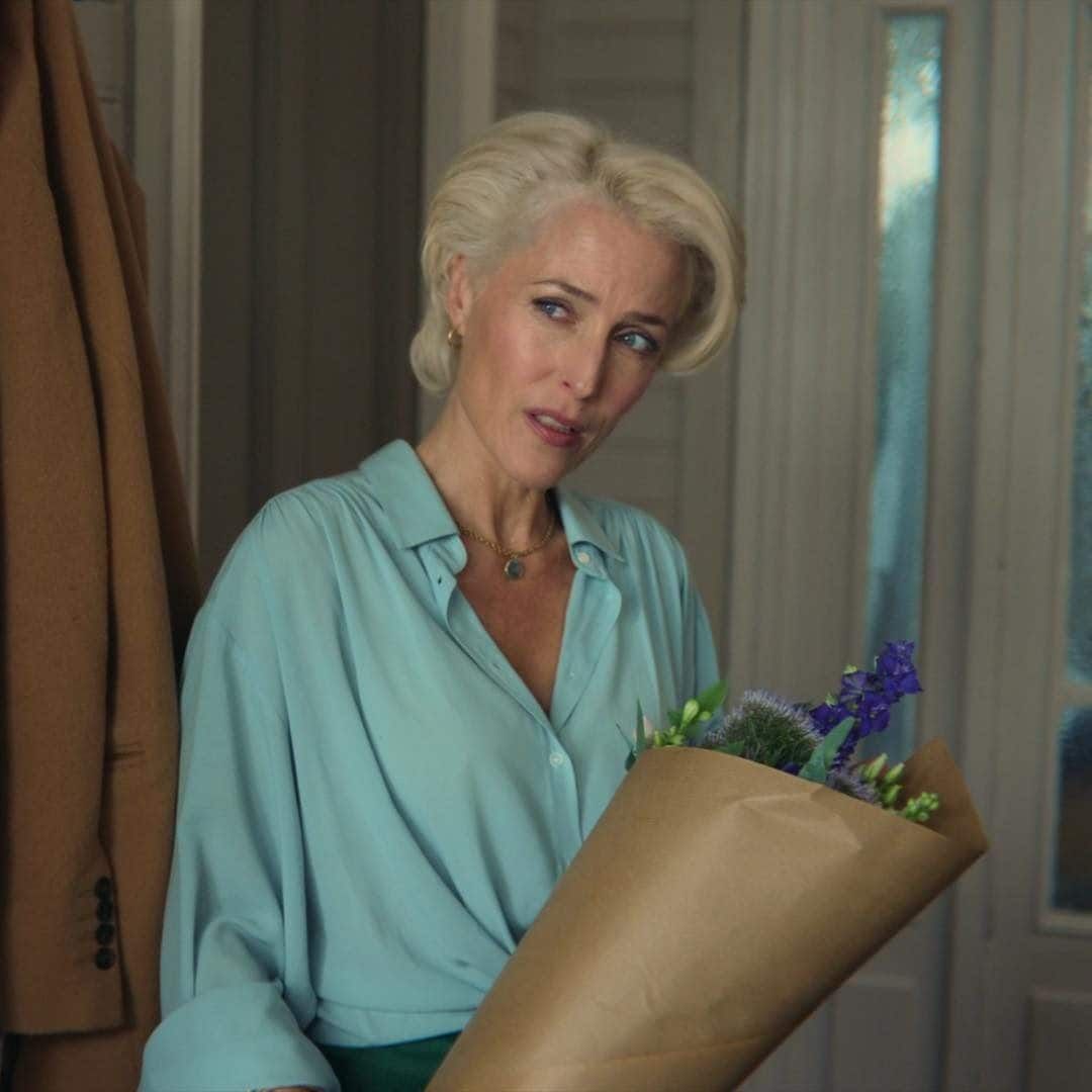 a woman in a blue shirt holding a brown paper bag