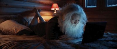 a man with a long white beard using a laptop on a bed