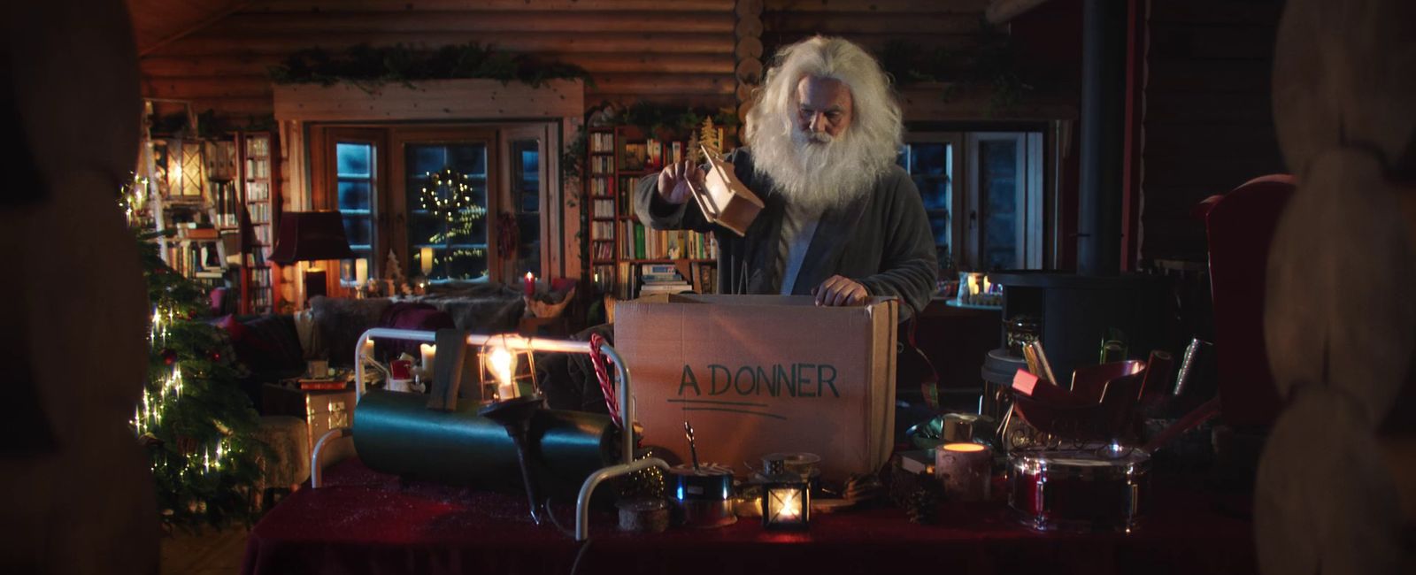 a man with a long white beard standing in front of a table