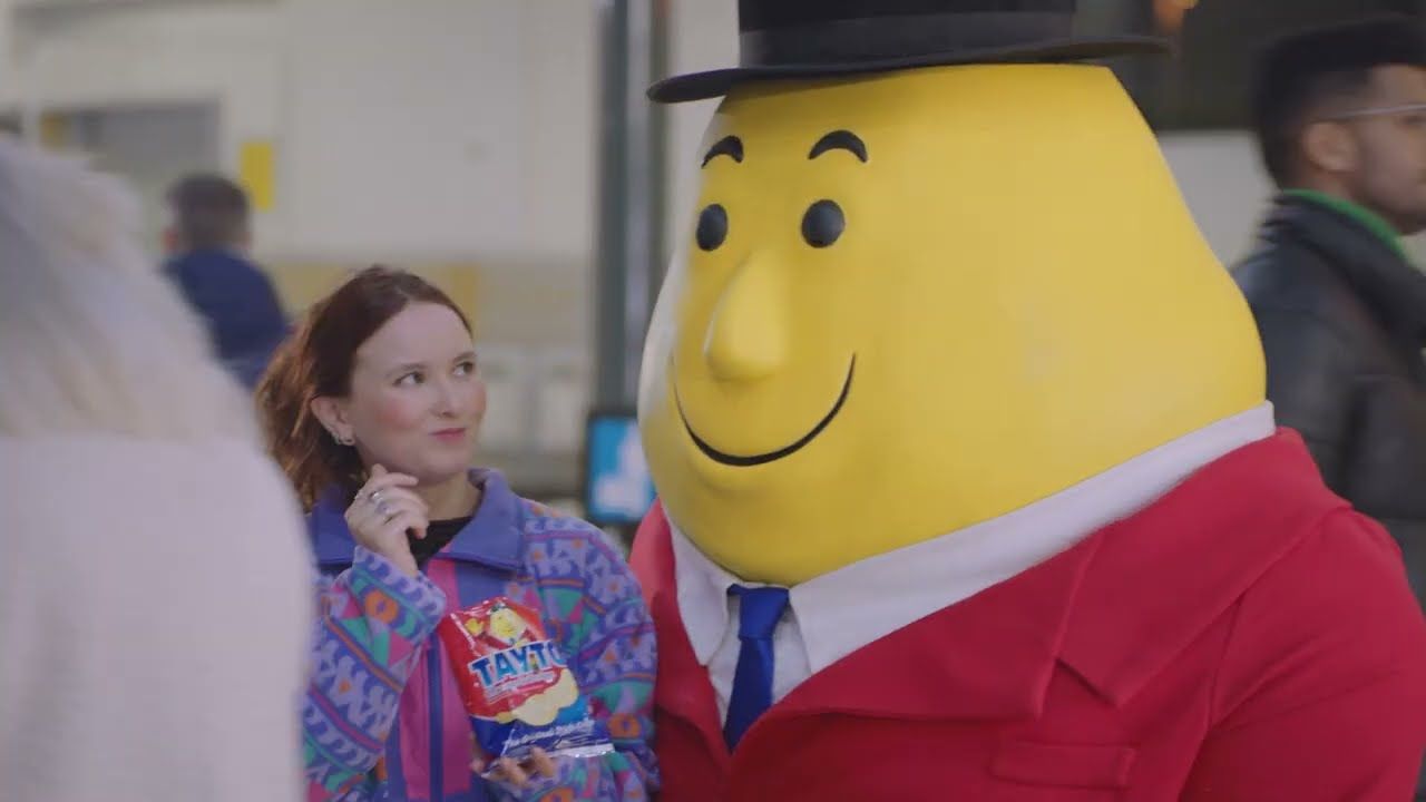 a woman standing next to a giant yellow character