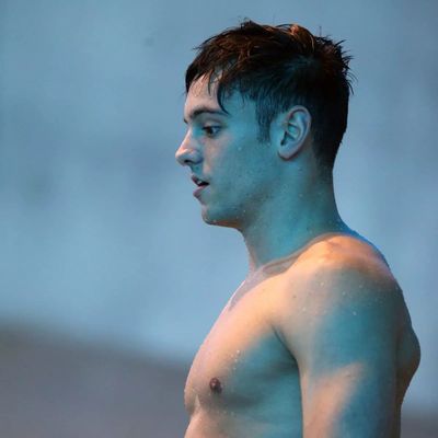 a man without a shirt standing next to a swimming pool