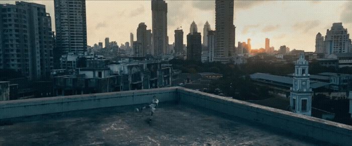 a man standing on top of a roof next to a tall building