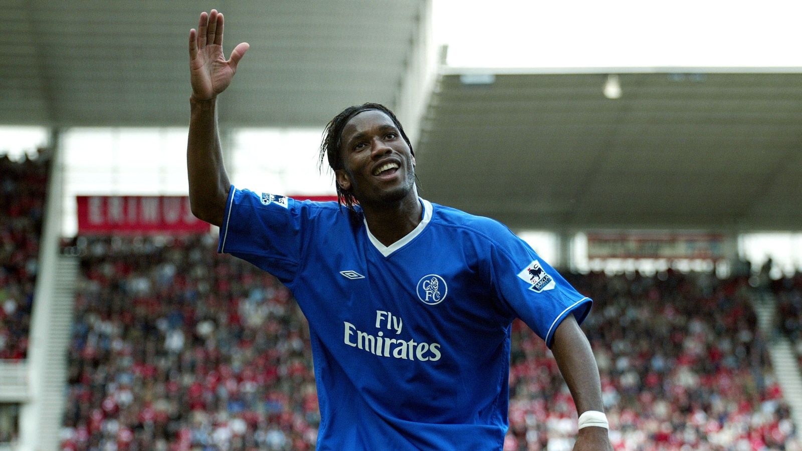 a man in a blue soccer uniform waves to the crowd