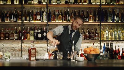 a man is making a drink at a bar