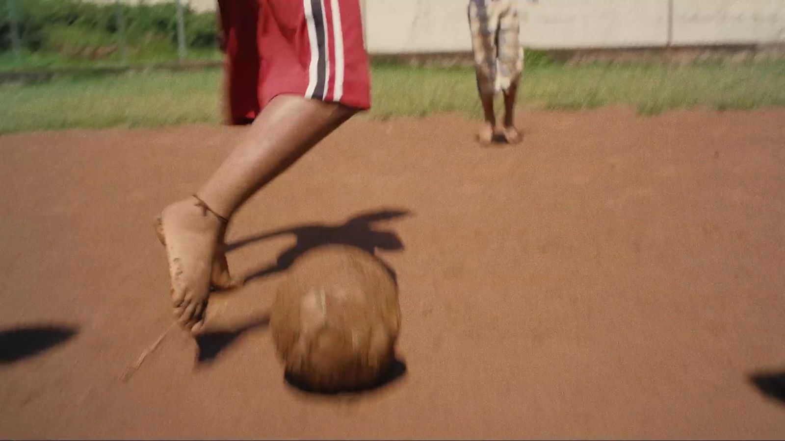 a person kicking a soccer ball on a dirt field