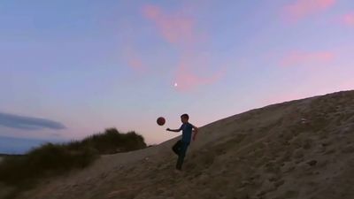 a man is playing with a ball in the sand