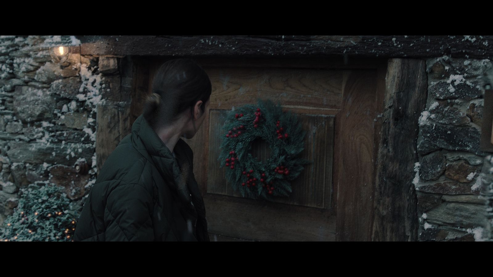 a person standing in front of a door with a wreath on it