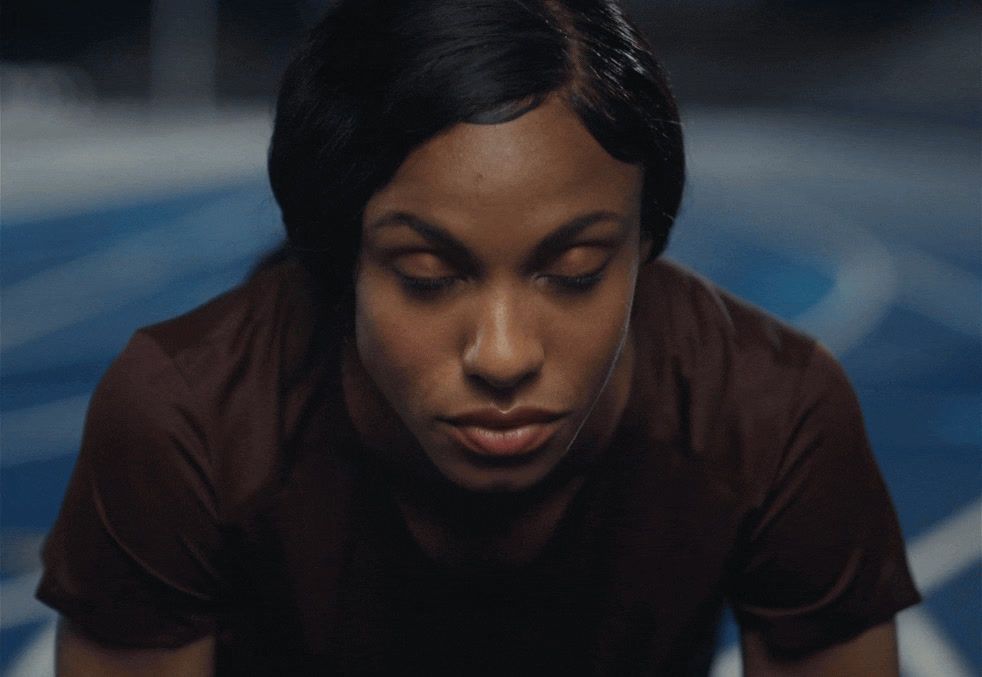 a woman in a brown shirt looking down at her cell phone