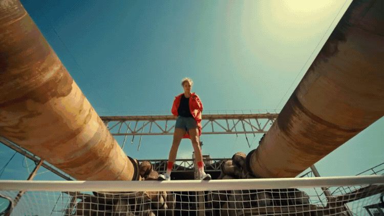 a man standing on top of a boat next to pipes