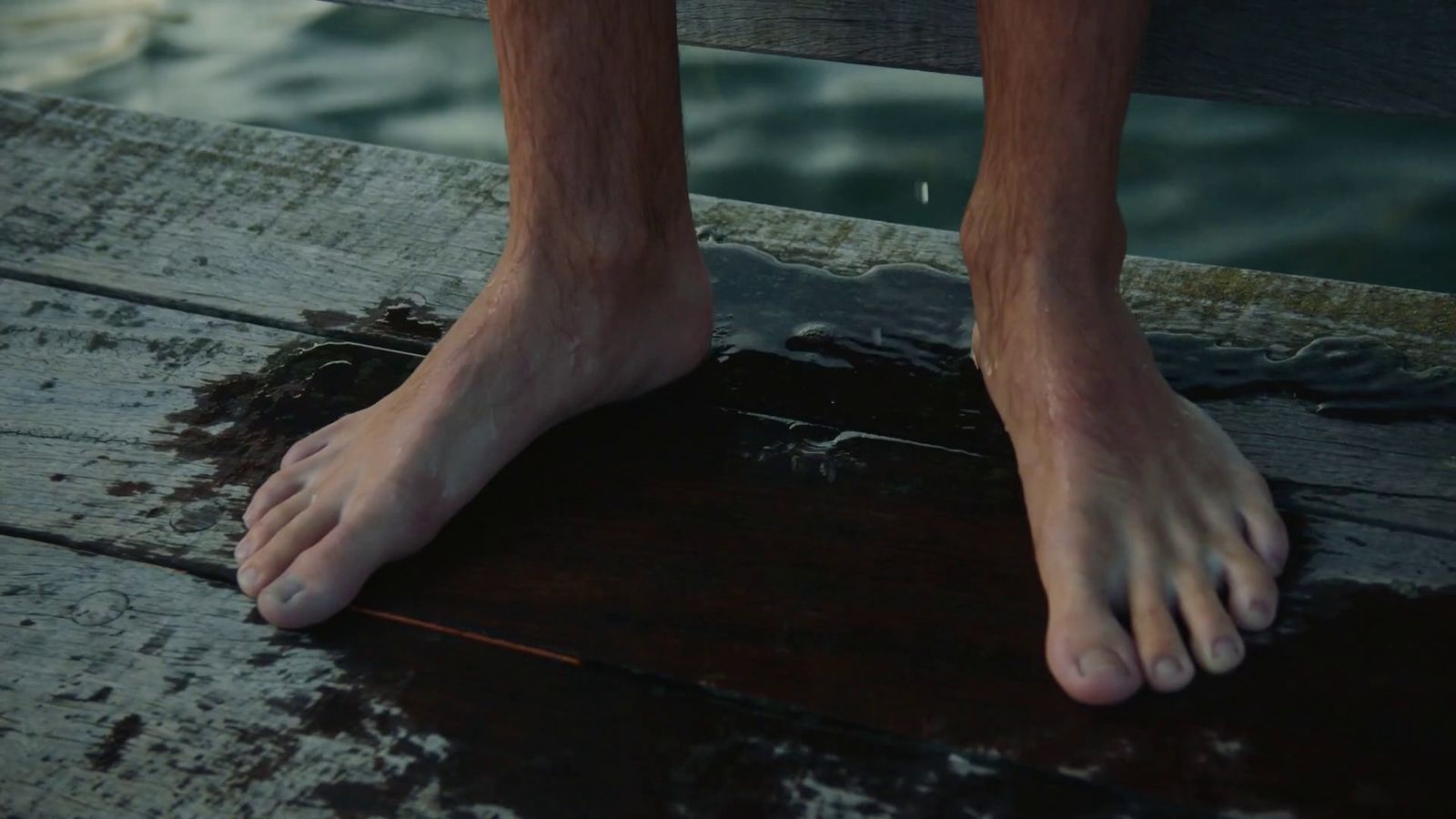 a close up of a person's bare feet on a dock