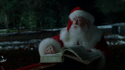 a man dressed as santa claus reading a book