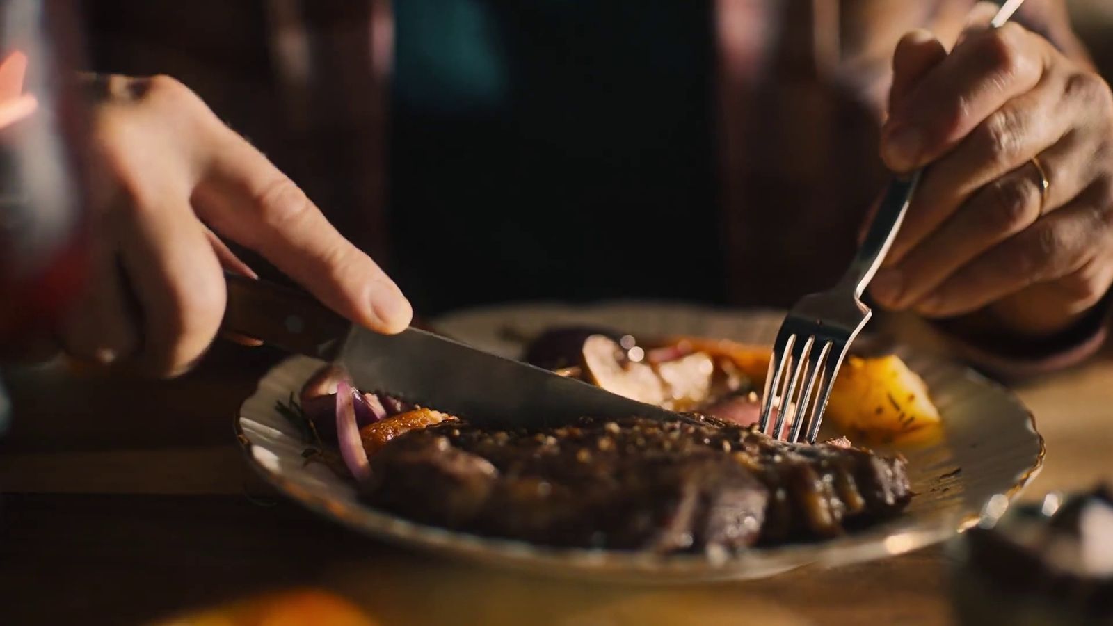 a person cutting a steak with a knife and fork