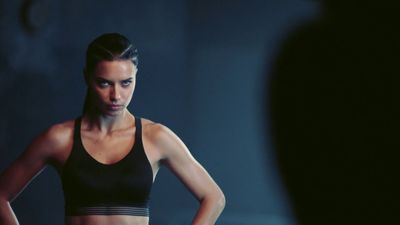 a woman in a black sports bra looking at her reflection