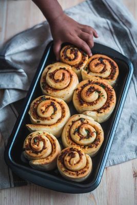 a pan filled with cinnamon rolls on top of a wooden table