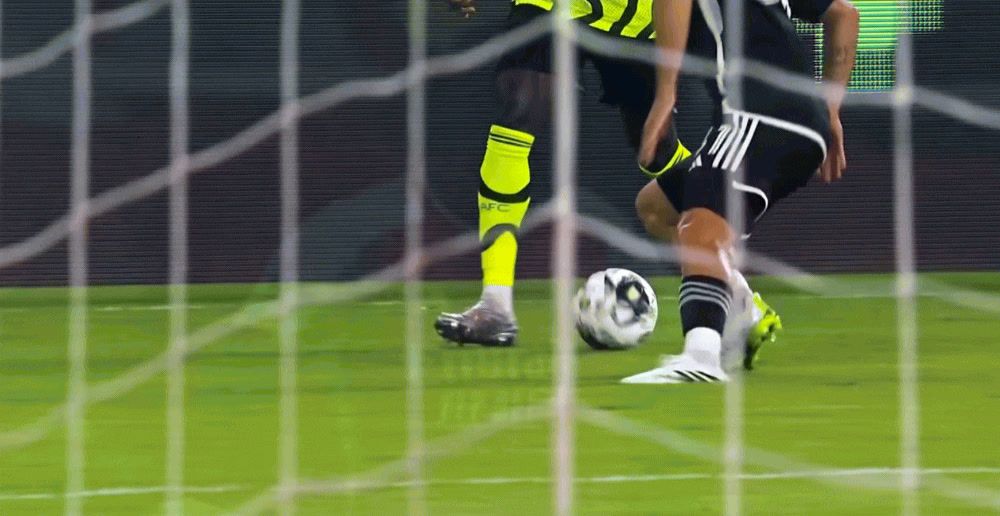 a man kicking a soccer ball across a field