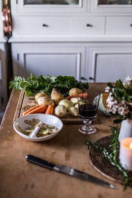 a wooden table topped with a bowl of food and a glass of wine