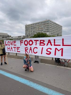 a woman kneeling down next to a sign that reads love football hate racism