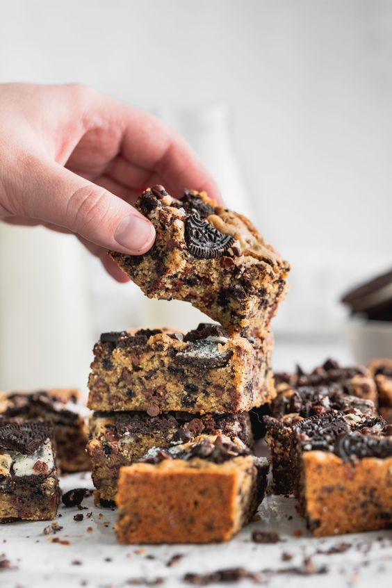 a hand picking up a cookie bar from a pile