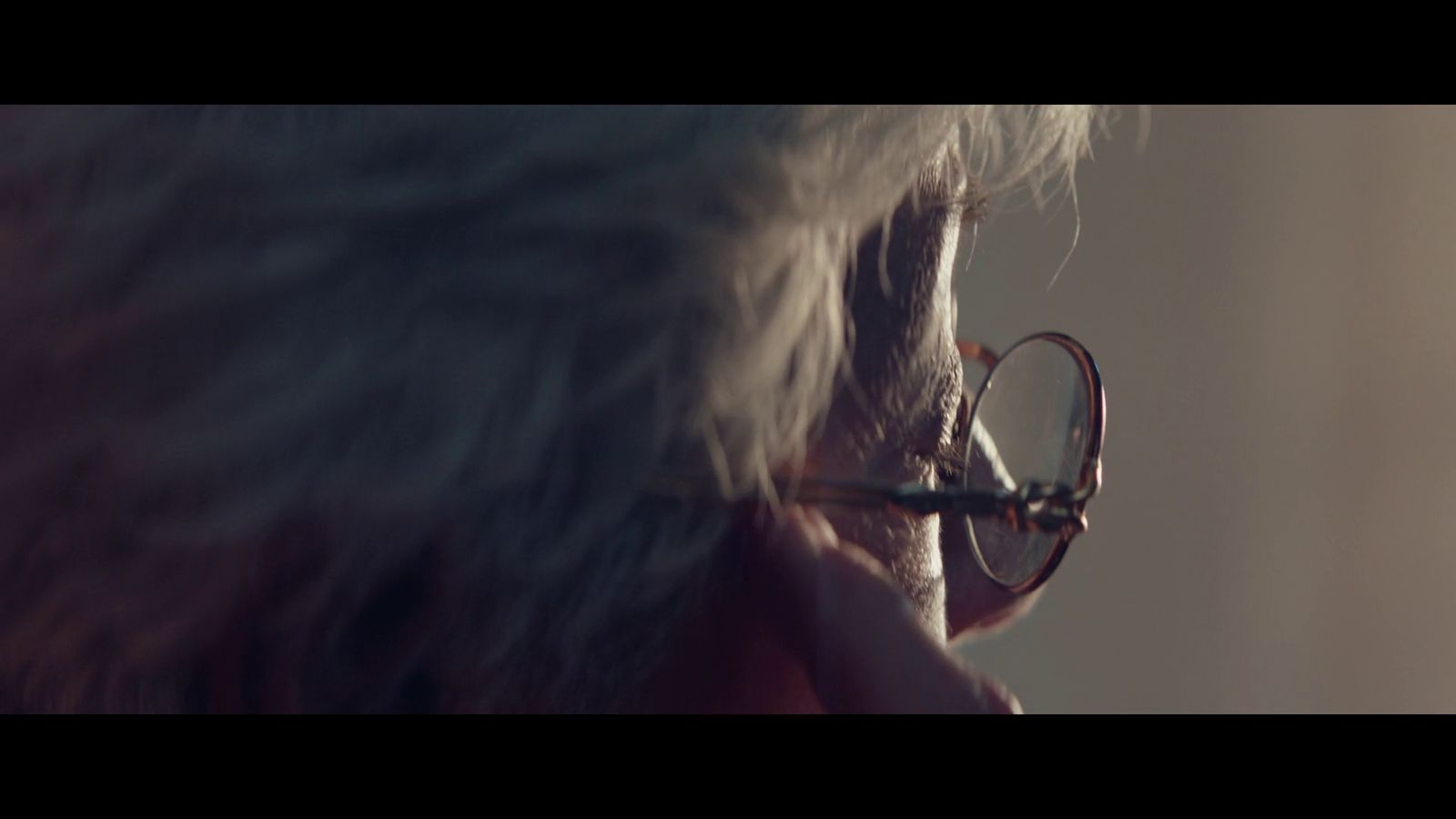 a man with glasses looking out of a window