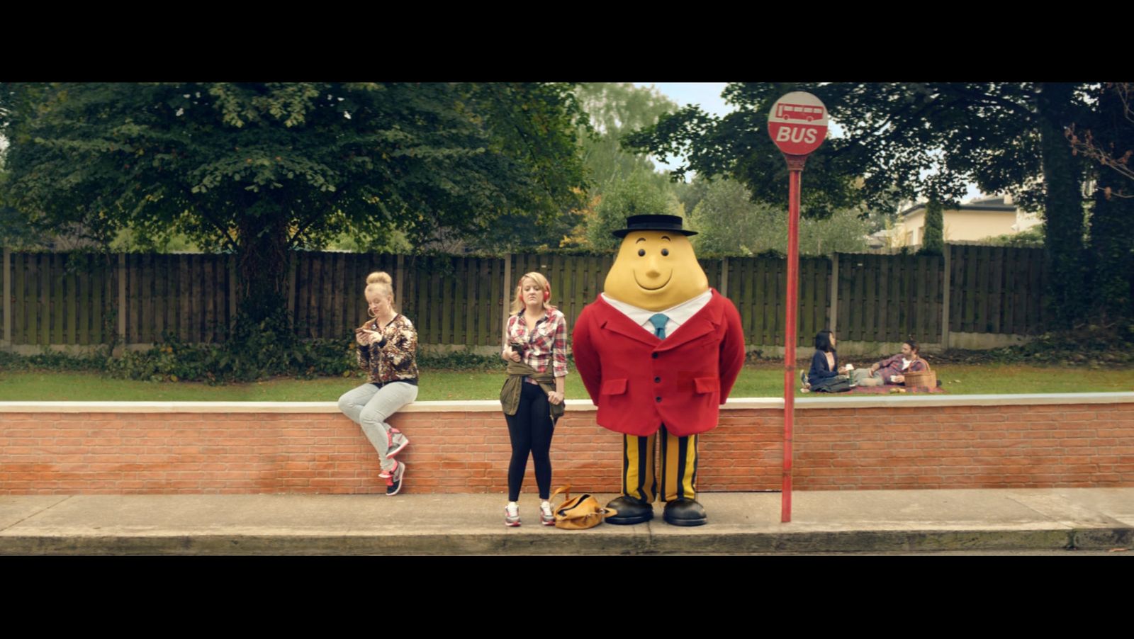 two women sitting on a bench next to a large statue of winnie the pooh