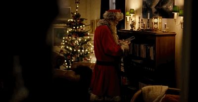 a man dressed as santa claus standing in front of a christmas tree