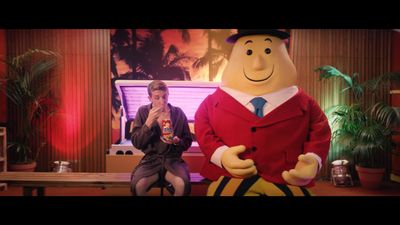 a woman sitting next to a giant cartoon character