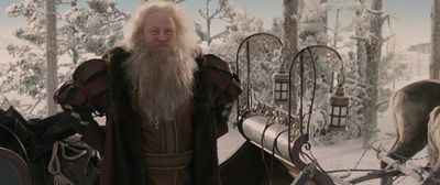 a man with a long white beard standing in front of horses