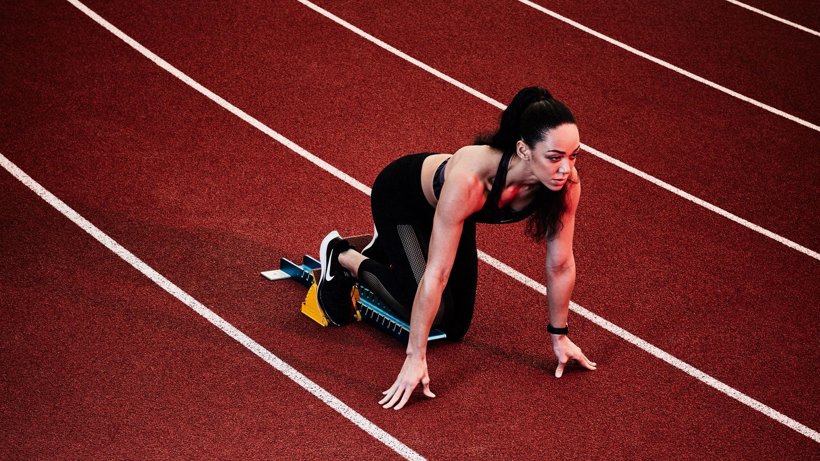 a woman kneeling down on a running track