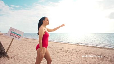 a woman in a red swimsuit walking on a beach