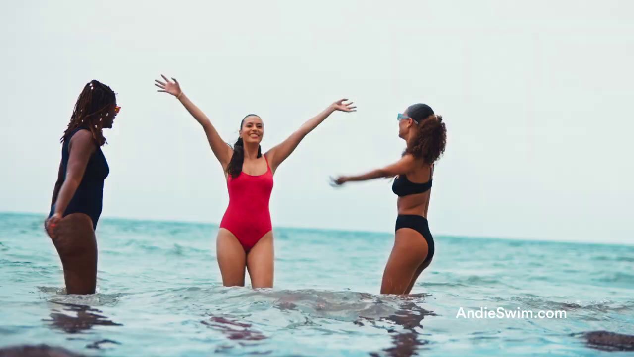 three women in a bodysuit standing in the ocean